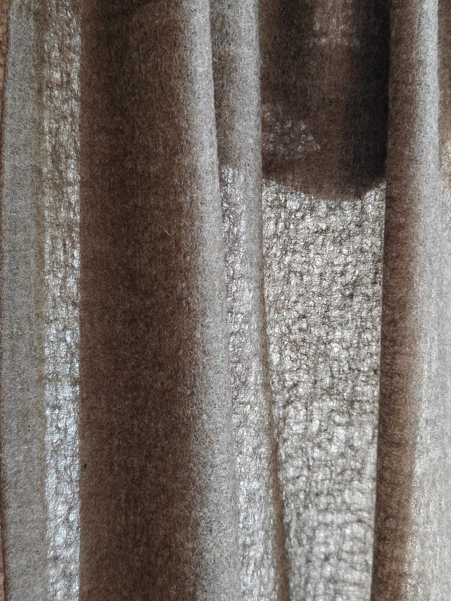 Close up of a natural brown cashmere shawl featuring a soft brushed texture, rich fiber detail, and warm earthy tones. The draped cashmere fabric highlights the quality, thickness, and artisanal character of this premium wrap.
