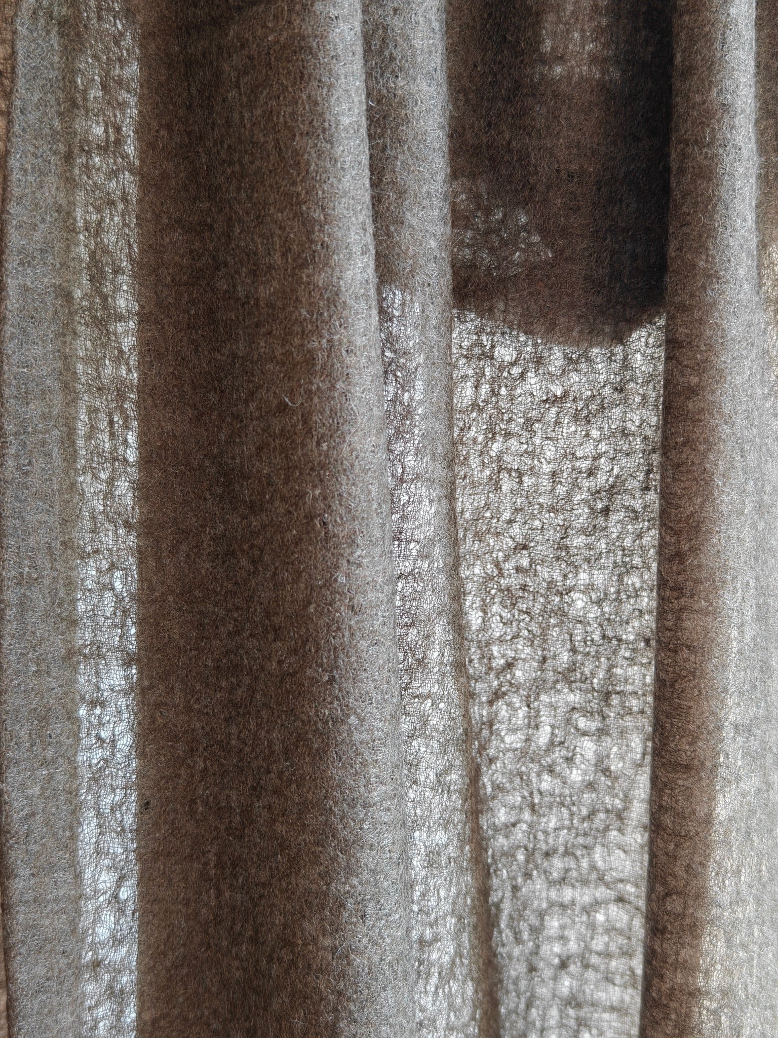 Close up of a natural brown cashmere shawl featuring a soft brushed texture, rich fiber detail, and warm earthy tones. The draped cashmere fabric highlights the quality, thickness, and artisanal character of this premium wrap.