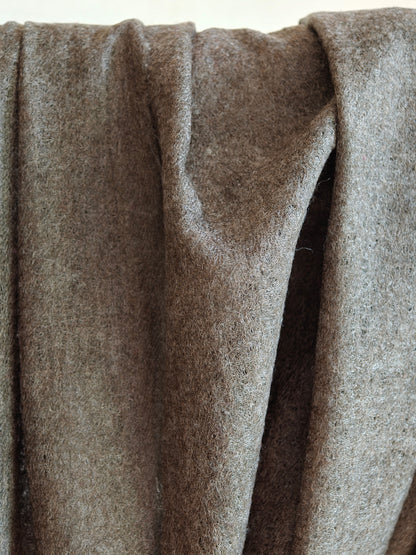 Detailed view of a lightweight brown cashmere shawl showing its semi sheer weave, airy texture, and natural wool fibers. Light filtering through the fabric emphasizes its breathability, softness, and handcrafted quality.