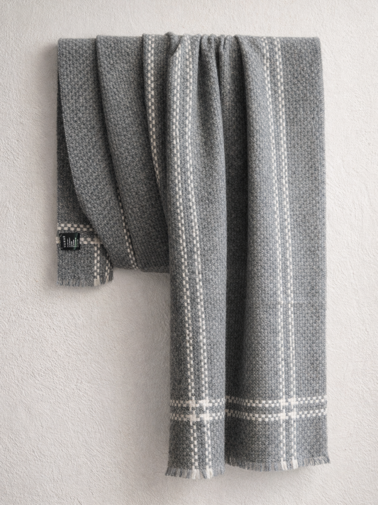 Gray cashmere wrap with white patterns draped over a light gray surface