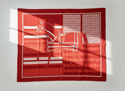Red wool blanket with white horse design on a textured wall background