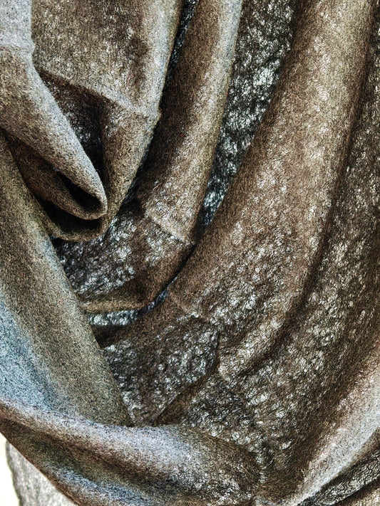 Draped cashmere fabric showing rich charcoal brown tones and airy gauze texture for a soft and elegant wrap.