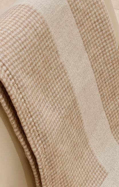 A close up of the fawn wool throw showing its soft houndstooth weave and warm neutral tones. The detailed texture highlights its cozy, lightweight warmth.