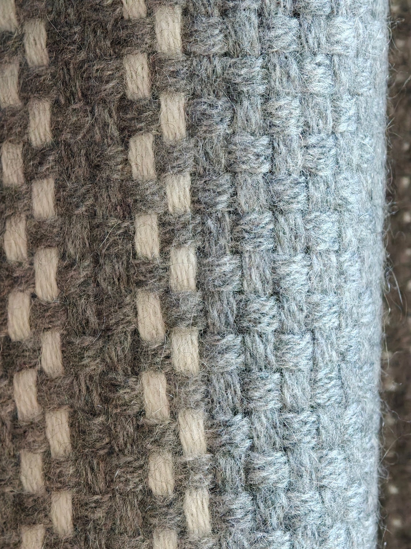 A detailed close up of the gray cashmere wrap showing its soft woven texture and ivory plaid accents. The image highlights the natural loft, warmth, and craftsmanship of the Inner Mongolian cashmere fiber.