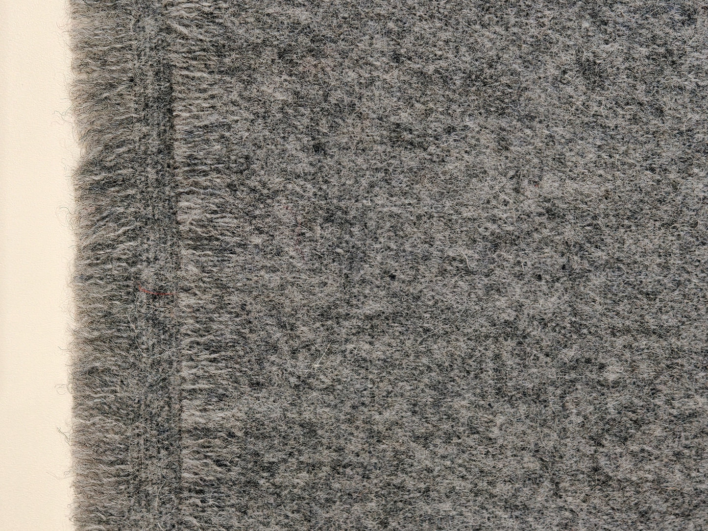 A close up of the gray wool throw highlighting its brushed weave and plush surface. The detailed texture shows the warmth, softness, and natural character of the wool fibers.