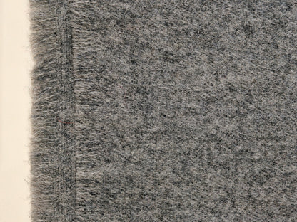 A close up of the gray wool throw highlighting its brushed weave and plush surface. The detailed texture shows the warmth, softness, and natural character of the wool fibers.