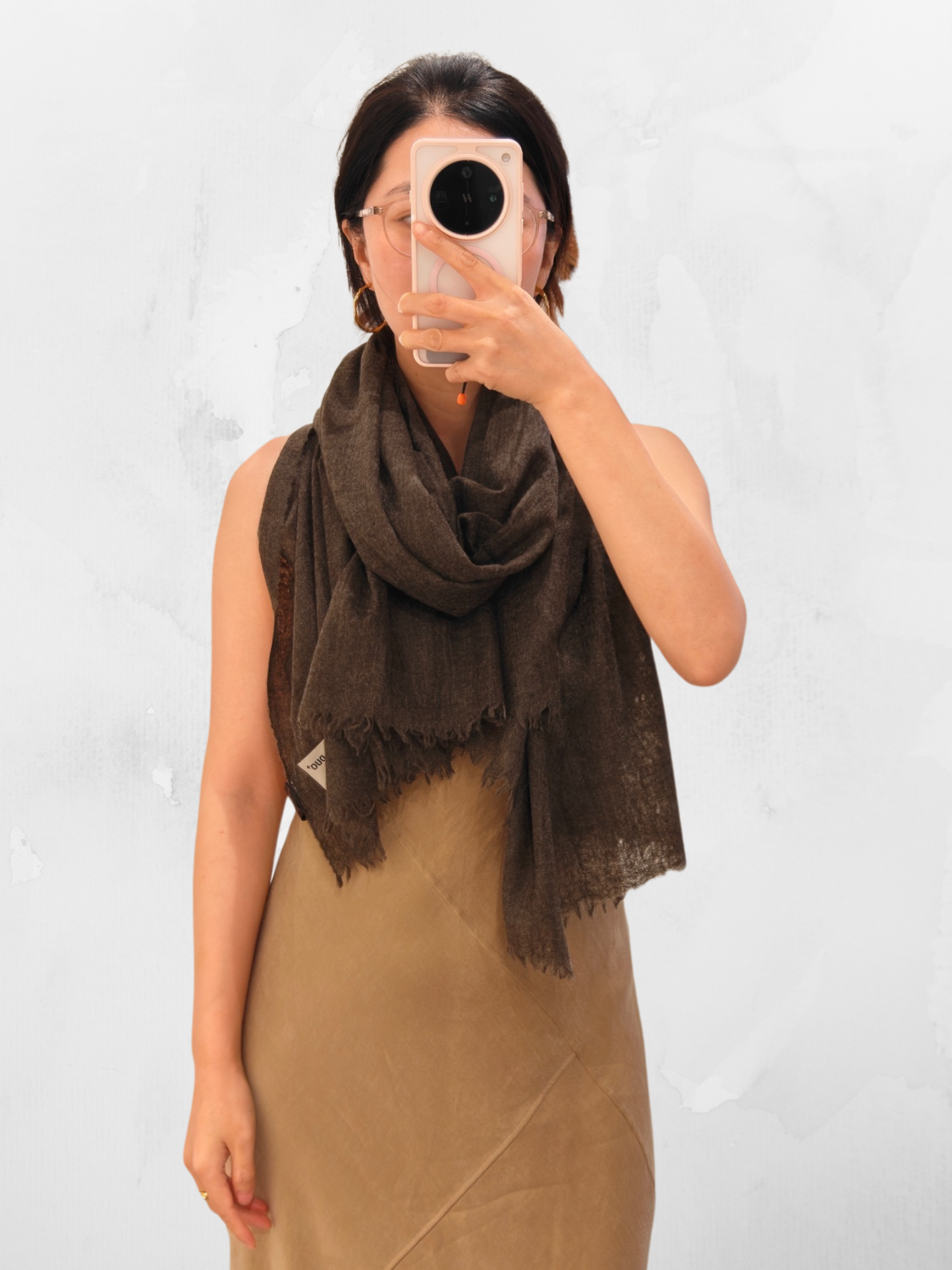 A natural brown cashmere shawl draped on a model in a full body view, showing the lightweight semi sheer texture and soft drape of the cashmere wrap.