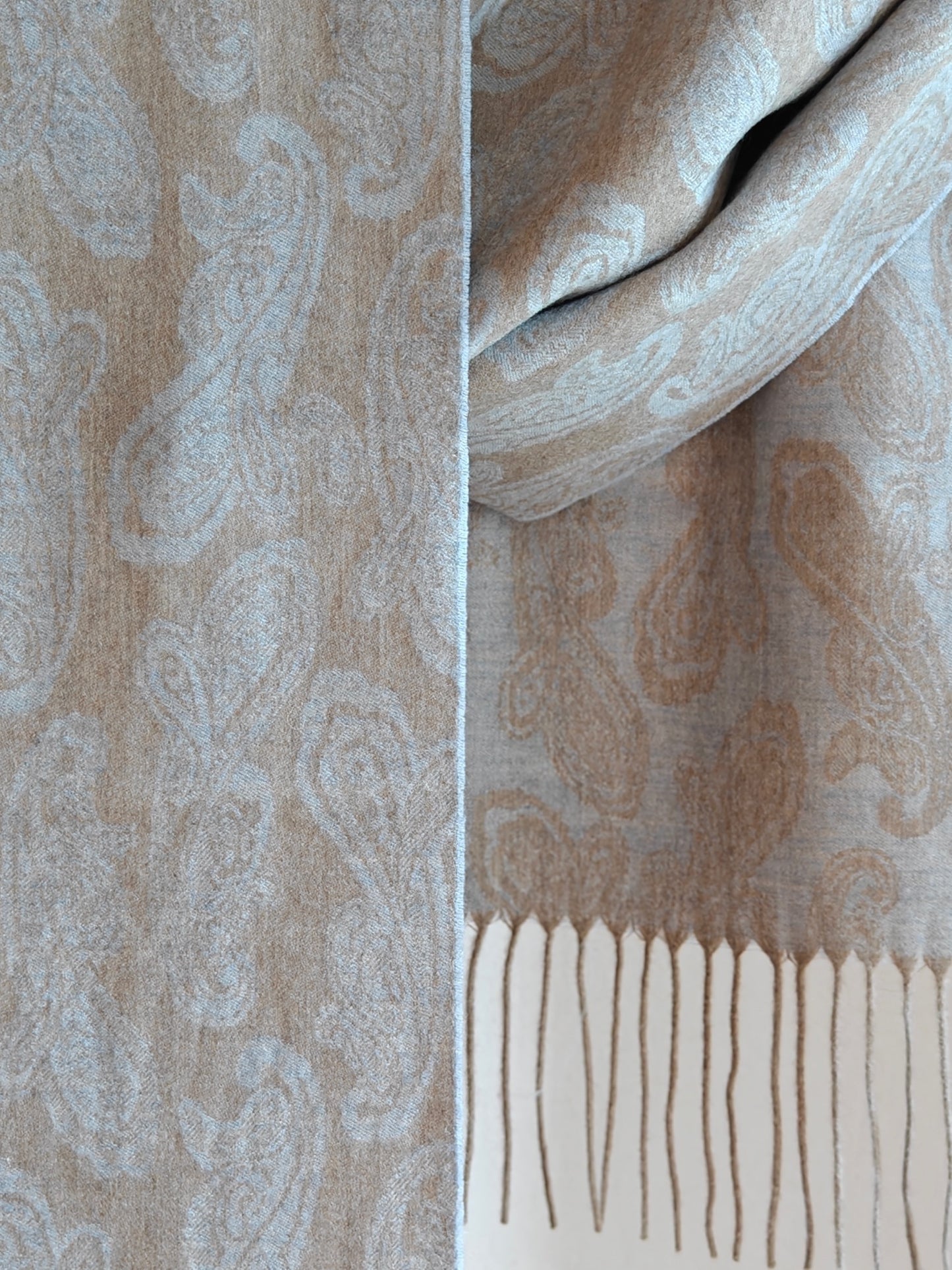 Close up of a pure cashmere paisley scarf from Duo Plus in soft beige and powder blue tones. Shows the fine woven paisley pattern and lightweight luxurious cashmere texture.