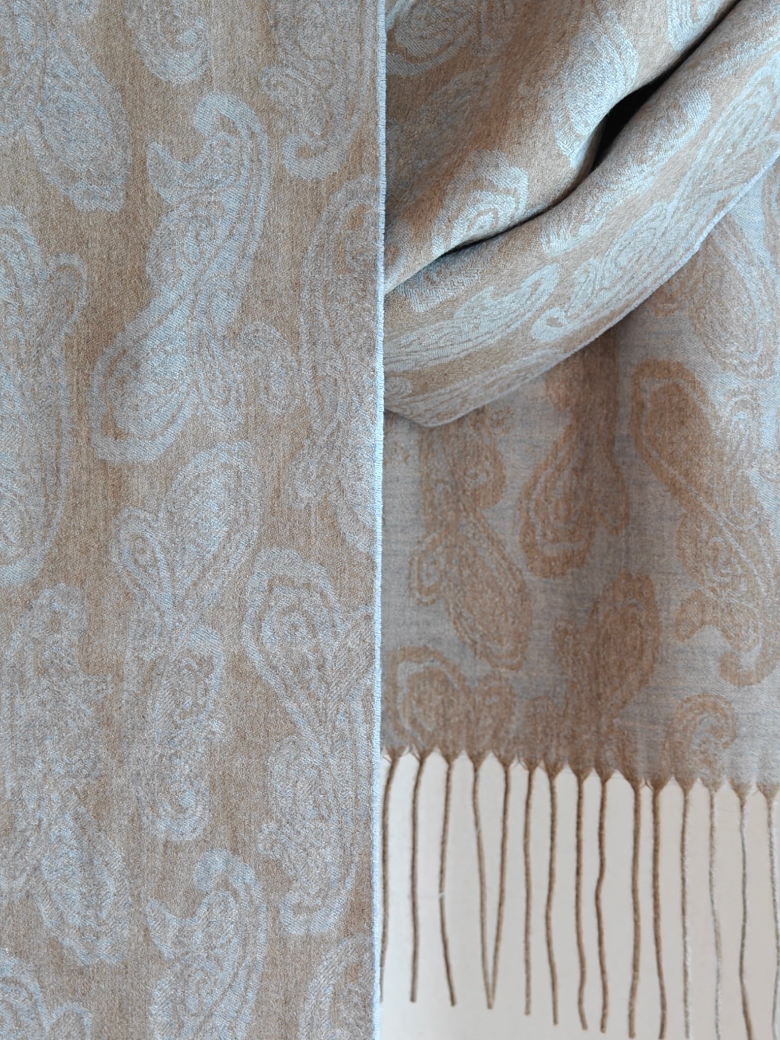 Close up of a pure cashmere paisley scarf from Duo Plus in soft beige and powder blue tones. Shows the fine woven paisley pattern and lightweight luxurious cashmere texture.