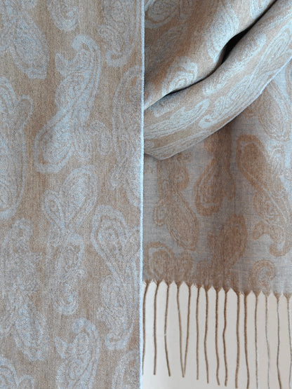 Close up of a pure cashmere paisley scarf from Duo Plus in soft beige and powder blue tones. Shows the fine woven paisley pattern and lightweight luxurious cashmere texture.