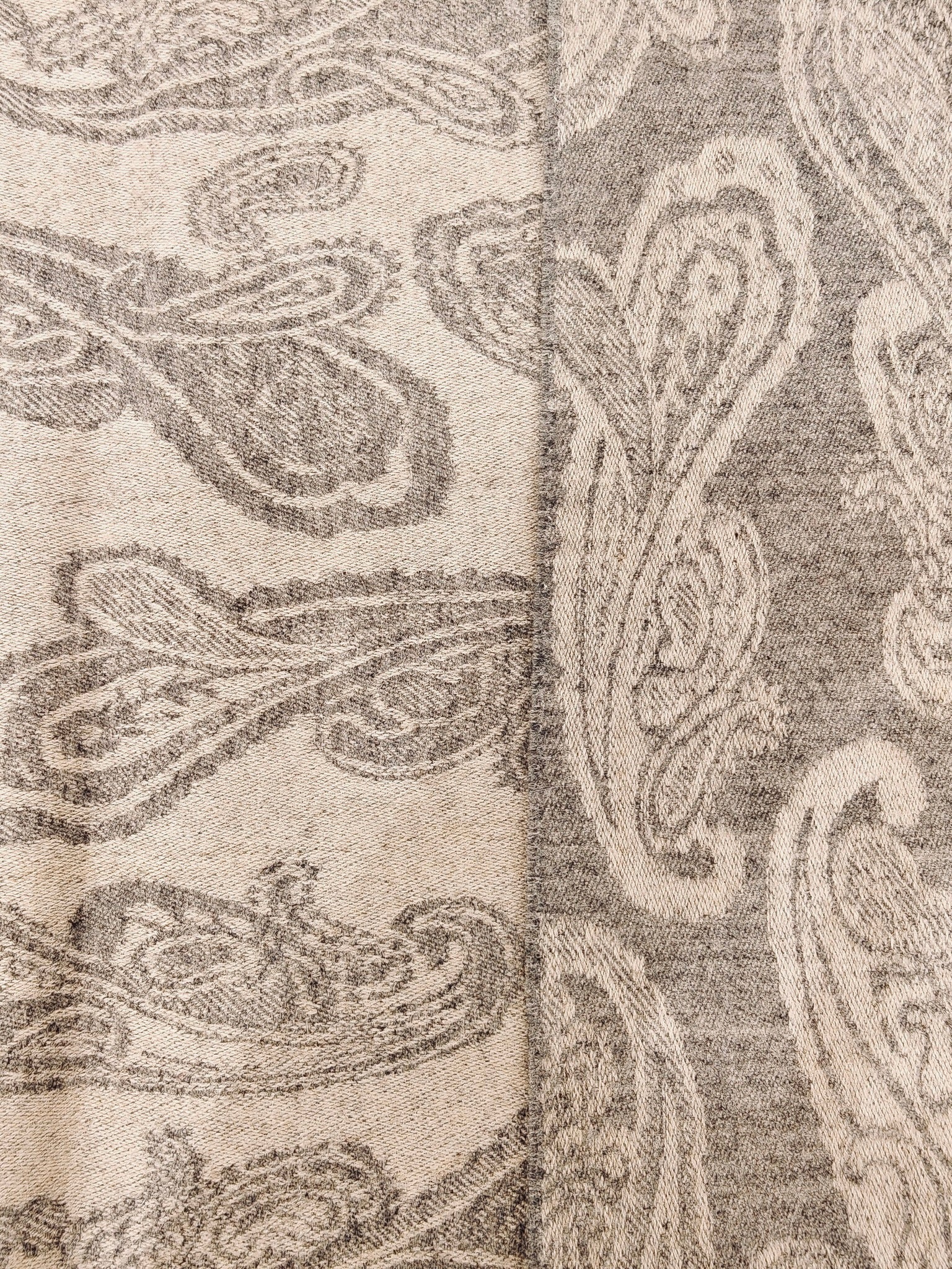 Pattern detail of a pure cashmere paisley scarf showing its reversible brown and taupe design. The woven paisley texture and fine cashmere fibers enhance its premium look.