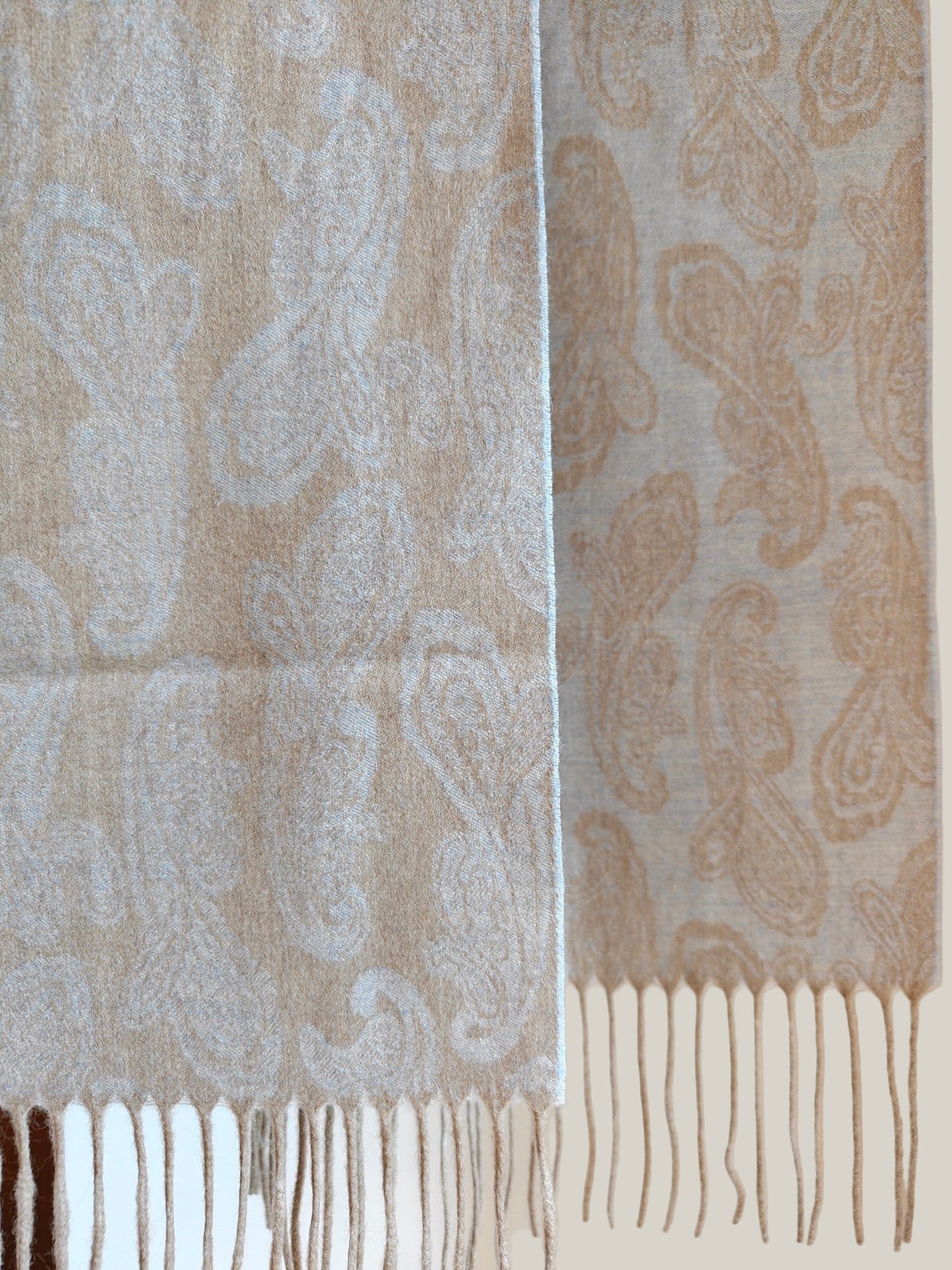 Pure cashmere paisley scarf hanging to show the full woven pattern and long fringe detail. Features a refined beige and blue palette crafted from soft Inner Mongolian cashmere.