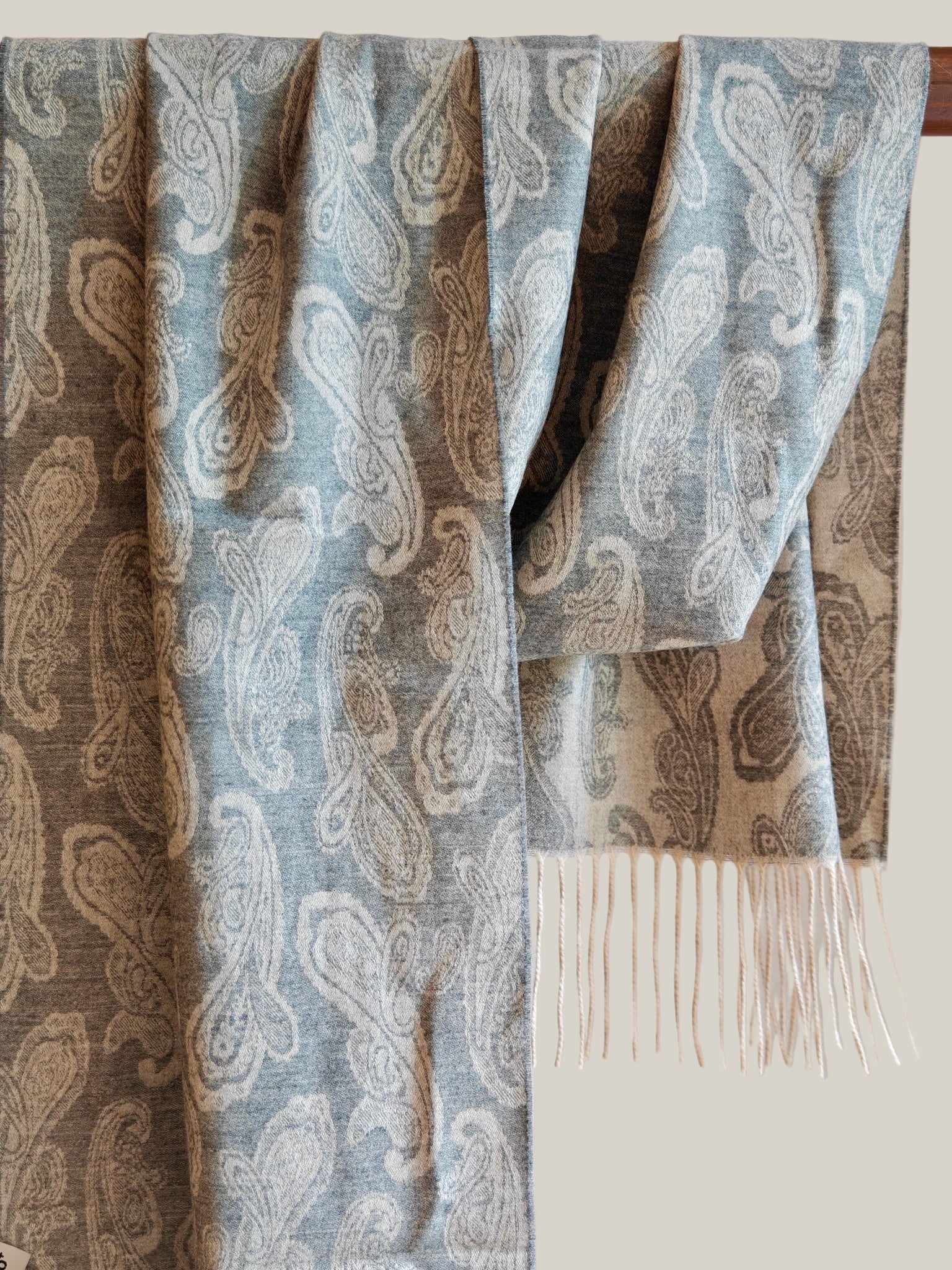 Pure cashmere paisley scarf in blue gray hanging to show the full reversible pattern and soft fringe. Crafted from premium Inner Mongolian cashmere for lightweight warmth.