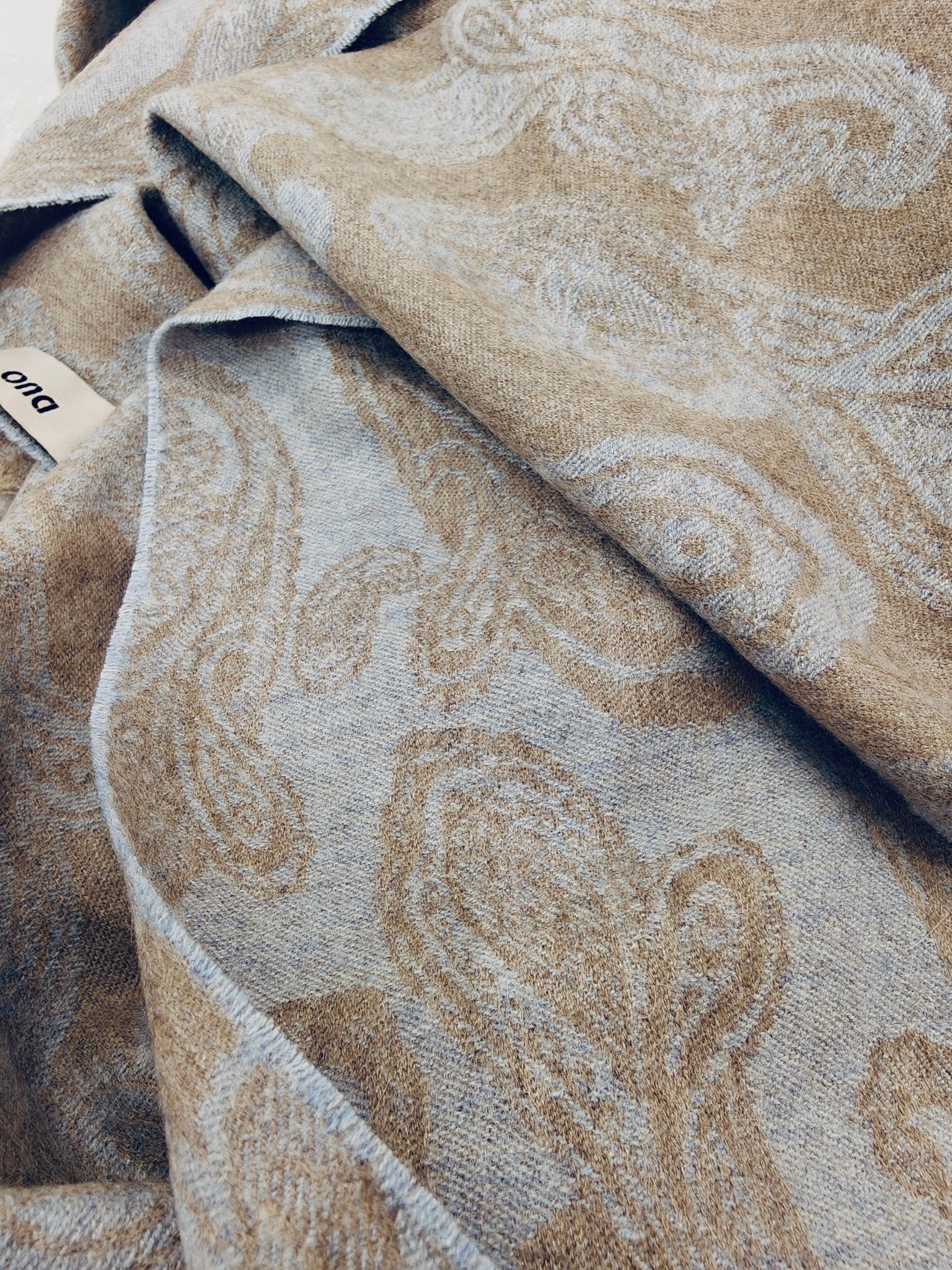 Pure cashmere paisley scarf displayed in a relaxed draped style, highlighting the smooth hand feel and reversible beige and blue woven design. Premium Inner Mongolian cashmere from Duo Plus.