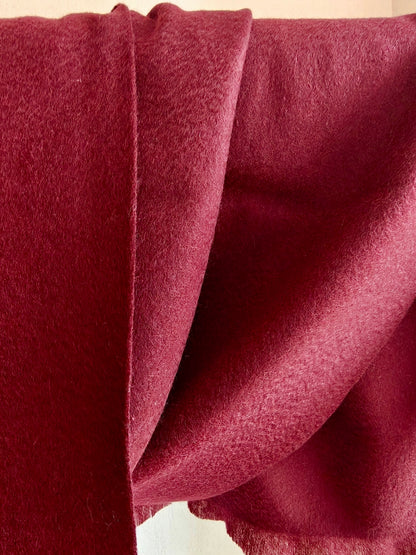 Red pure cashmere scarf hanging to display its smooth drape and velvety brushed surface. The rich crimson tone and clean edges highlight the timeless elegance of Duo Plus cashmere.