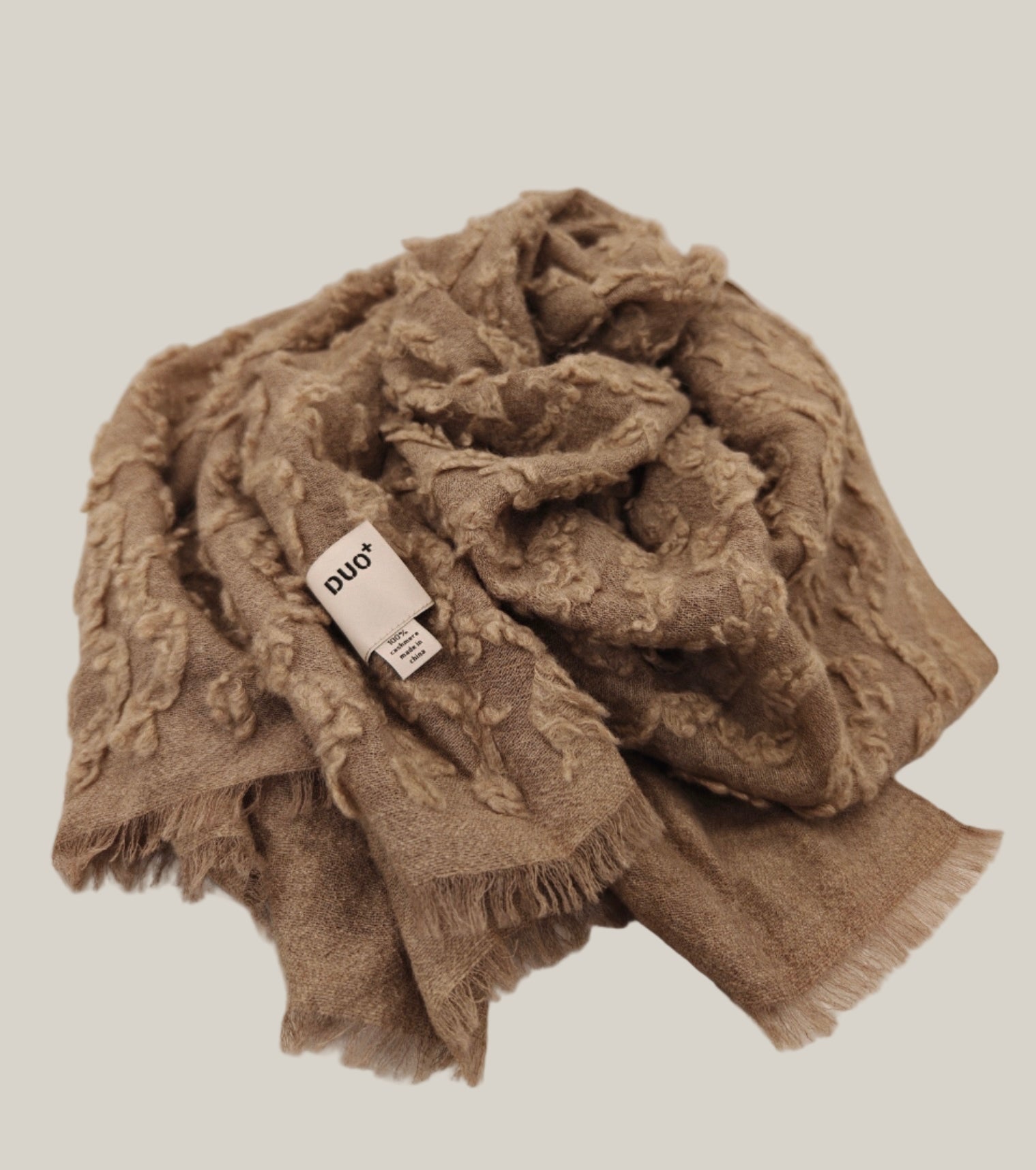 A folded view of the Ripples Cashmere Wrap with the Duo Plus label visible. The image showcases the raised ripple weave and the wrap’s plush, artisanal finish.