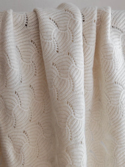 Soft draped view of the ivory yak wool blend shawl hanging over a rod, focusing on its scalloped knit and natural texture.