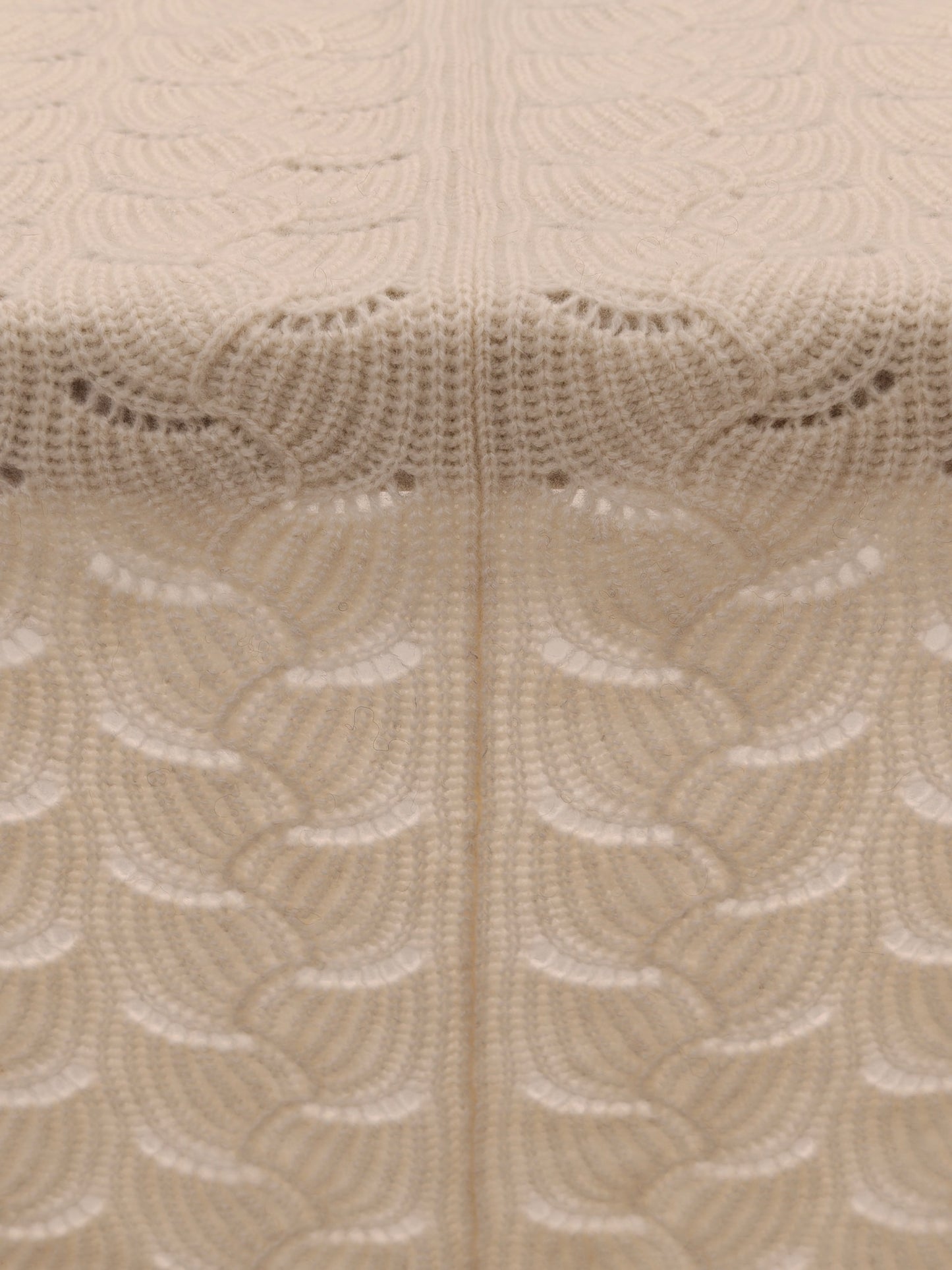 Full pattern view of the ivory yak wool blend shawl laid flat to highlight the scalloped knit structure and even stitching.