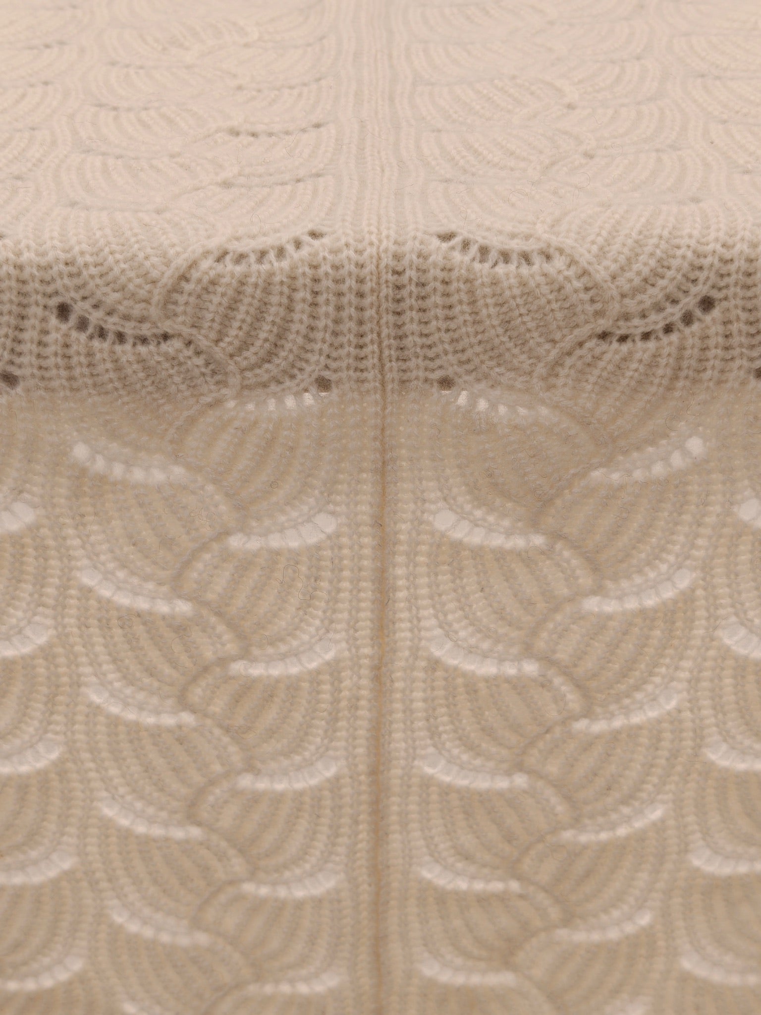 Full pattern view of the ivory yak wool blend shawl laid flat to highlight the scalloped knit structure and even stitching.