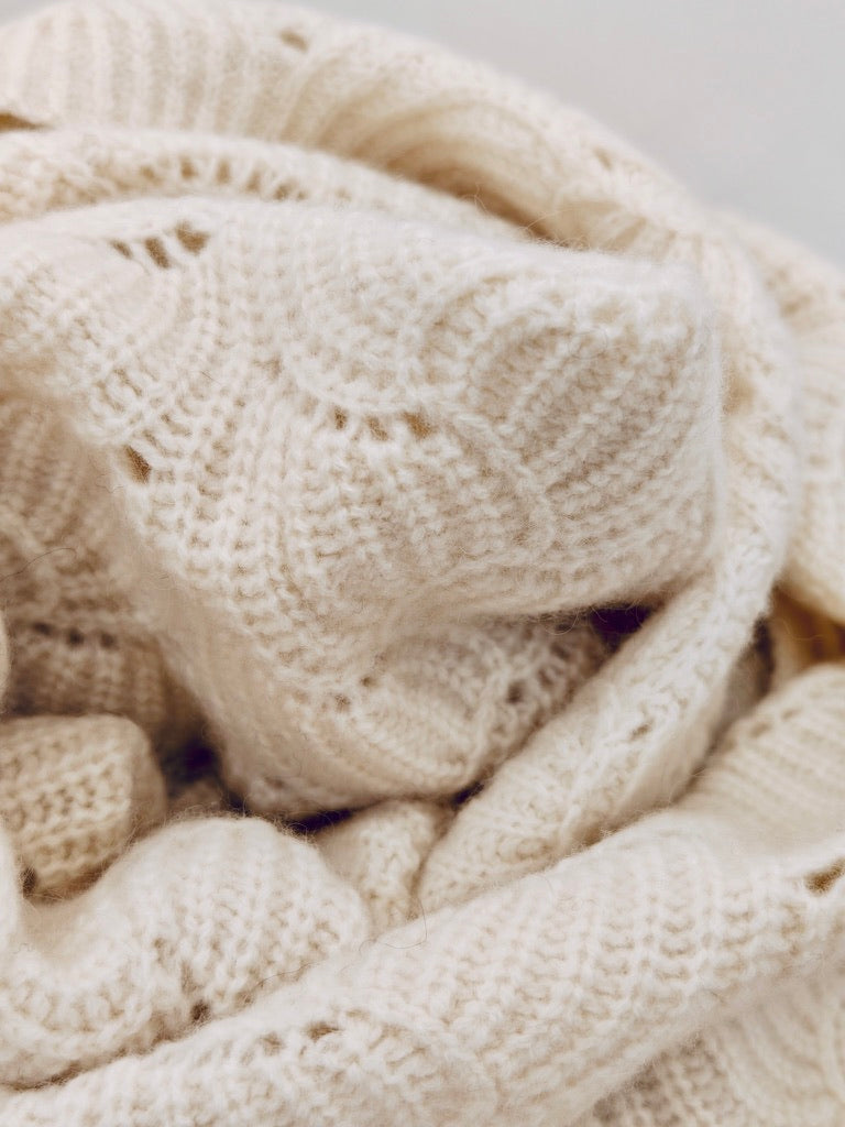 Close up of the ivory yak wool blend shawl showing its scalloped knit pattern and soft airy texture. Highlights the natural loft and craftsmanship.